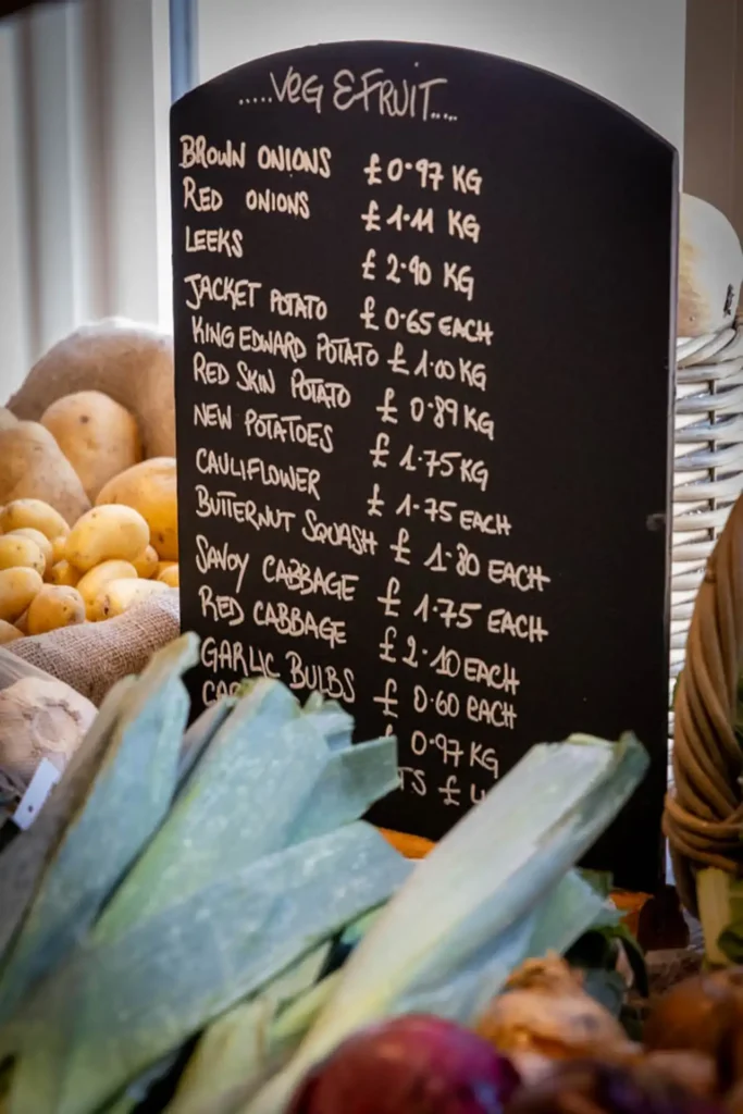 Leeks, red onions and seasonal vegetables beside the price chalkboard at Ashdon Farm Shop