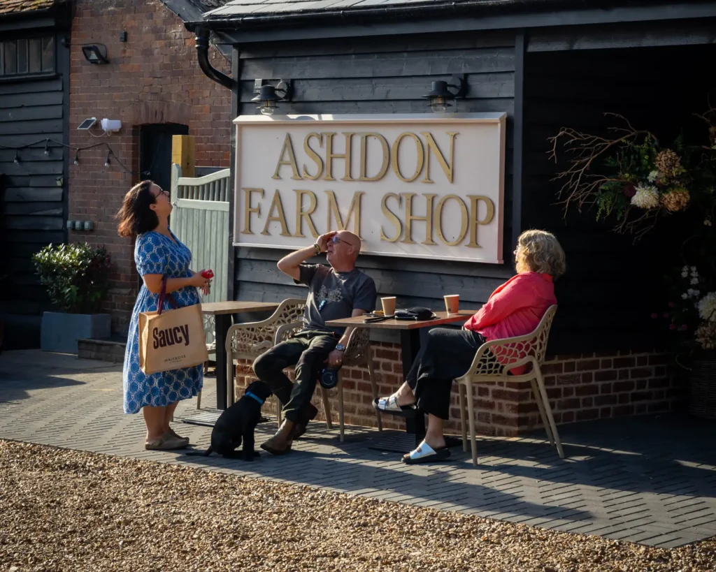 Customers sitting outside Ashdon Farm Shop, a black weatherboarded building at Crown Hill, Ashdon